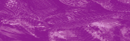 Blur of a vibrant purple lace fabric featuring intricate patterns with shimmering highlights, creating an elegant and luxurious texture in soft folds.の写真素材