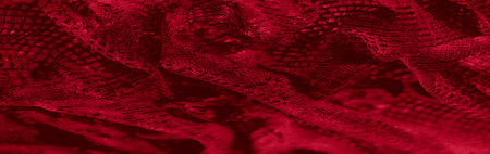 Blurred abstract details of red textured fabric with intricate weaving and bold patterns. The dynamic folds and rich colors exude luxury and artistic charm.の写真素材