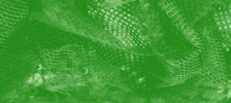 Blurred vibrant green mesh fabric with dynamic patterns and a shimmering effect. The textured layers and glowing highlights create an artistic and contemporary appeal.の写真素材