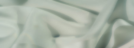 Blur of soft, pastel green fabric artfully arranged in folds and flowing layers, emitting an organic...