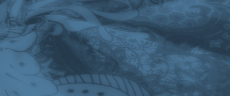 Blurred smooth blue fabric featuring artistic floral patterns and swirling paisley motifs, creating a flowing and decorative textile ideal for modern designs.の写真素材