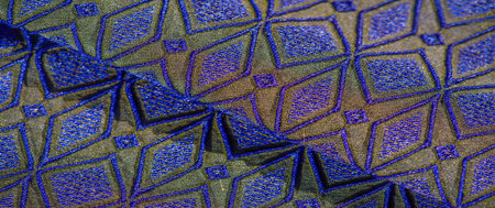 Blur, the fabric's design combines a vibrant interplay of gold and blue diamond-shaped patterns with...