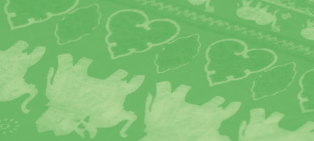 Blurred close-up of smooth green fabric with a white floral design. The folds of the fabric create a soft and calming visual, emphasizing the elegance and texture of the textile.の写真素材