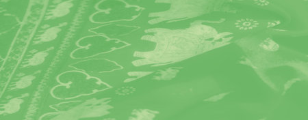 Blurred image of a gentle, green fabric with fine, white floral detailing, creating a soft and...