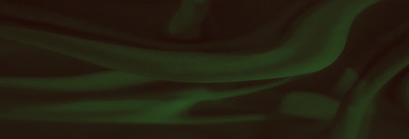 Blur of dark green fabric with smooth texture highlights its seamless drapery, flowing lines, and subtle folds that add depth and elegance to the abstract background.の写真素材