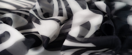 Blur of soft, folded fabric with a modern black and white striped pattern. The monochromatic tones...