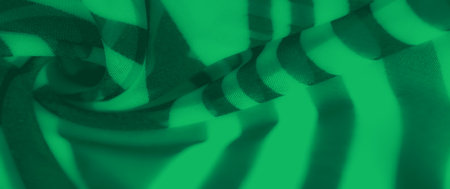 Blur - Sheer green fabric with striped patterns flows dynamically, showing soft folds and bold shadows that create depth and a sense of motion.の写真素材