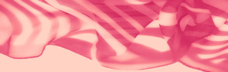 Blur of pink fabric with bold, curving striped patterns. The soft sheer texture and elegant folds capture light dynamically, creating an ethereal appearance.の写真素材