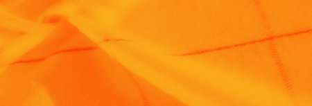 Blurred close-up of textured orange and yellow fabric with overlapping folds and vibrant hues, evoking energy and creativity in abstract visual compositions.の写真素材
