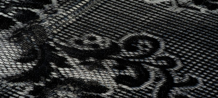 Blur of luxurious black lace fabric with delicate patterns, shimmering with light and creating an exquisite visual effect through its subtle folds and textures.の写真素材