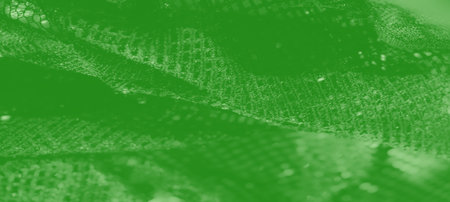 Blurred textured green fabric with sparkling details and a glowing sheen. The intricate mesh pattern adds a dynamic and contemporary touch to this artistic composition.の写真素材