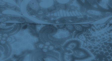 Blurred image of a delicate blue fabric with ornate patterns, showing flowing floral designs and...