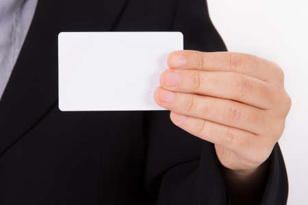 Business woman in dark suit shows white blank business card with space.の写真素材