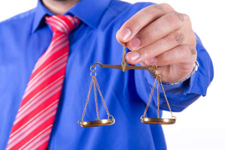 Businessman with red tie and blue shirt holding golden scales on balance, isolated on white background.の写真素材