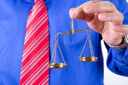 Businessman with red tie and blue shirt holding golden scales unbalanced, isolated on white background.の写真素材