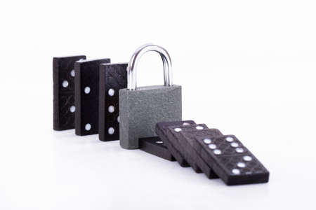 Damage control of black dominoes with padlock for security, isolated on white background.の写真素材
