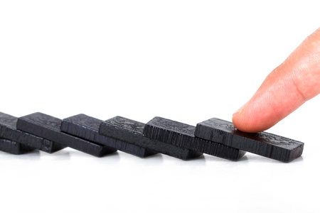 Fallen black dominoes and index finger, isolated on white background.の写真素材