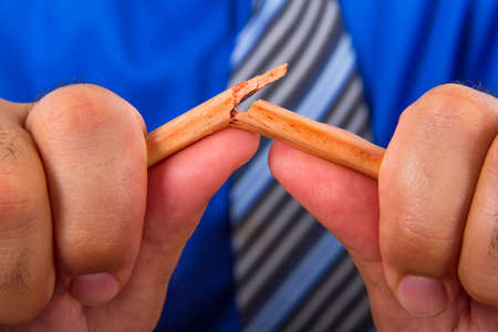 Businessman hand breaking yellow pencil.の写真素材