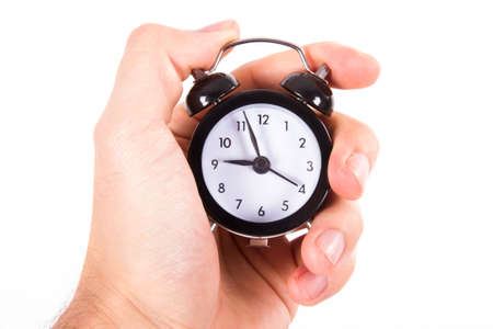 Hand holding old style fashioned alarm clock with black frame, isolated on white background.の写真素材