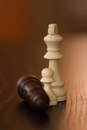 King and pawn defeats dark opponent on wooden table.の写真素材