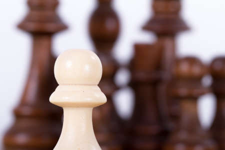 Close up view of single pawn against chess pieces on chess board, isolated on white background.の写真素材