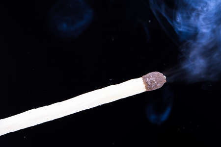 Burning match with smoke on dark background.の写真素材