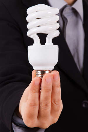 Business woman with smart suit holding and showing white economic light bulbの写真素材