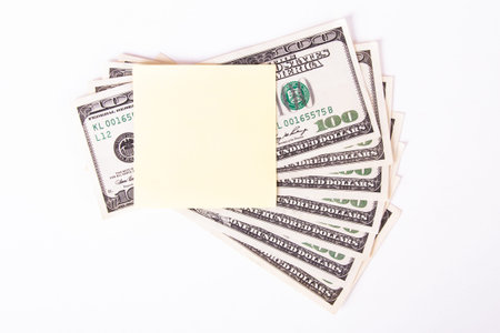 One hundred dollar bills with yellow, blank, empty sticky post it note for your message, isolated on...