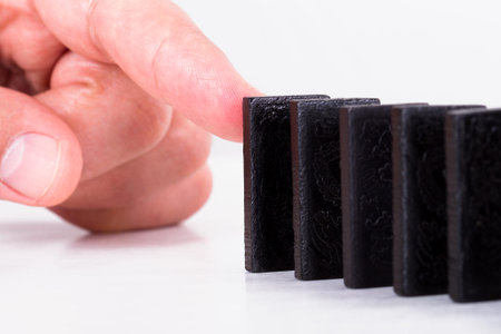 Finger pushing black dominoes, isolated on white background.
