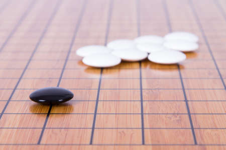 Black stone standing out from white pieces on Chinese go game board.の写真素材