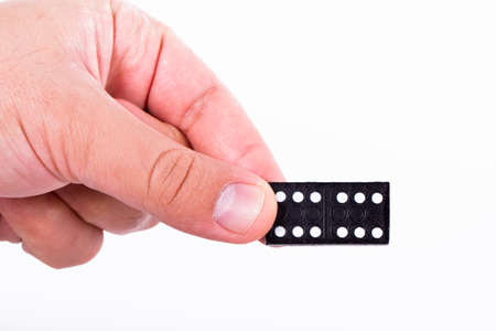 Hand holding black domino, isolated on white background.の写真素材