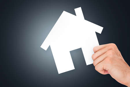 Hand holding white, empty, blank real estate cardboard on dark background.の写真素材