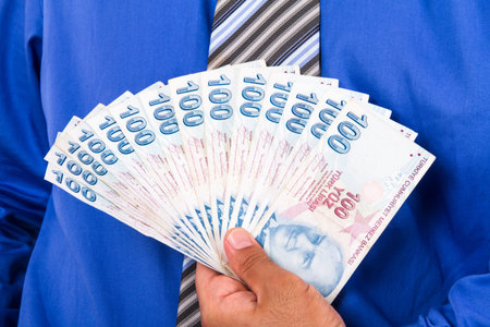 Businessman holding and showing one hundred Turkish liras banknotes.