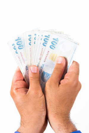 Businessman hand holding and counting one hundred Turkish liras banknotes, isolated on white...