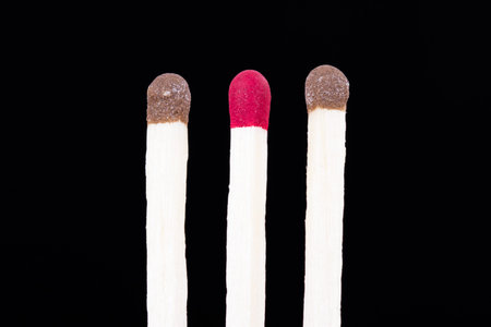 Leadership concept, red headed match standing out from the crowd on dark background.