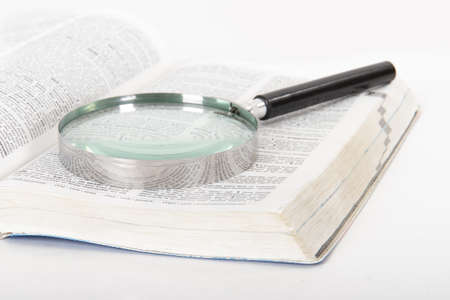 Classic style magnifying glass on open dictionary book, isolated on white background.の写真素材