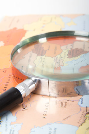 Classic style magnifying glass on map of Europe, isolated on white background.の写真素材