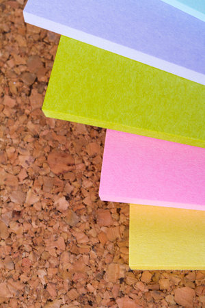 Multi colored sticky post it notes on cork bulletin board.