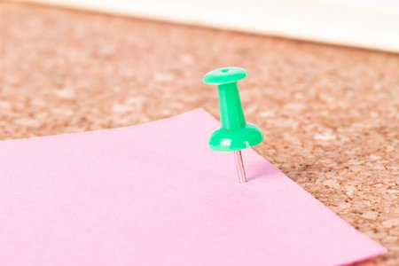 Green push pin and pink sticky post on cork bulletin board.の写真素材