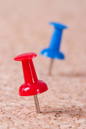 Red and blue push pins on cork bulletin board.の写真素材