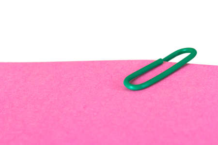 Close up view of pink sticky note with green paper clip, isolated on white background.の写真素材