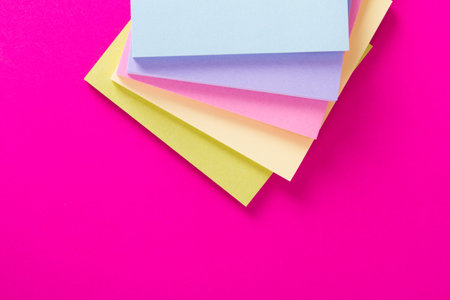 Stack of sticky post it blocks on pink background.