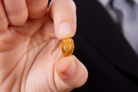 Business woman holding and showing yellow medical capsule.