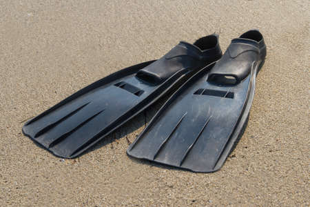 Black plastic flippers on sea sand.の写真素材