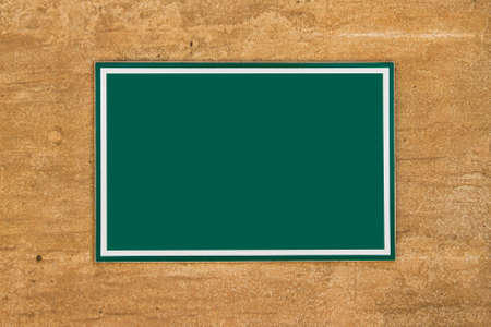 Blank green board sign with space on wall for your designs.の写真素材