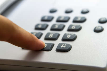Finger pressing phone key, telephone for customer service in hotel room.の写真素材