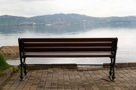 Empty wooden bench with viewpoint looking out to sea, cloudy weather.の写真素材