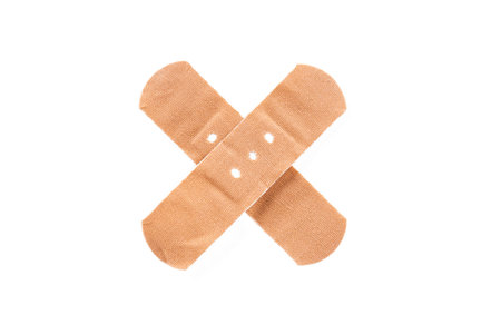 Adhesive bandage, plaster as cross sign, isolated on white background.の写真素材