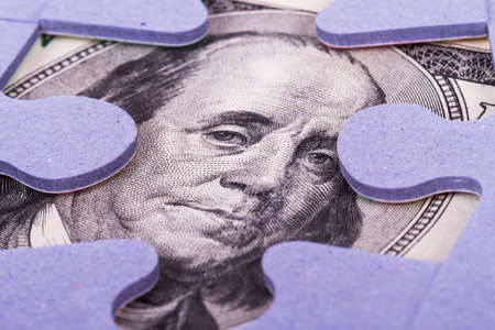 One  hundred dollar banknote between puzzle pieces.の写真素材