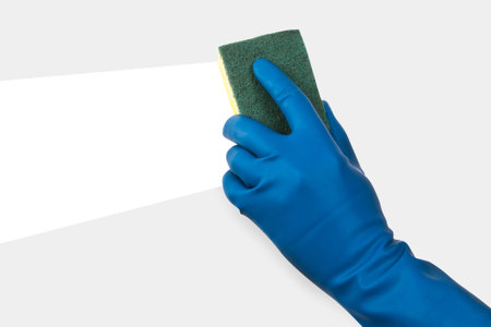 Hand in gloves holding sponge and cleaning dirty gray area.